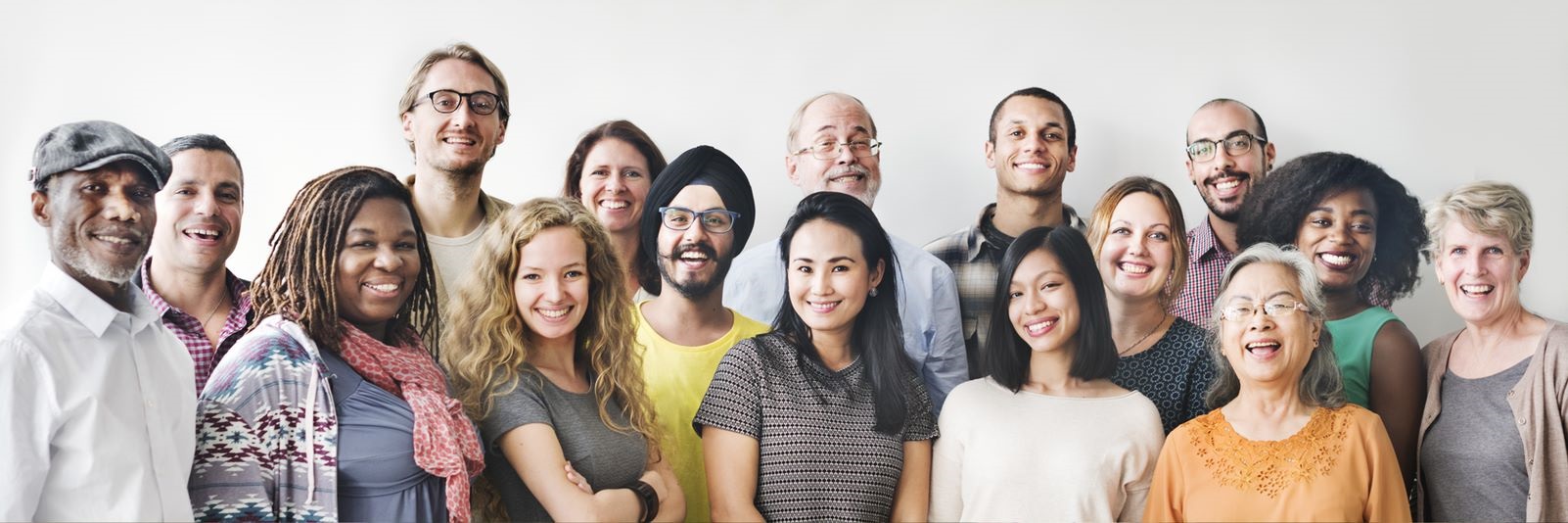 Group gathered with man wearing hat, women with brown hair, blonde hair, and black hair. Wearing different colored shirts and smiling with cream background.